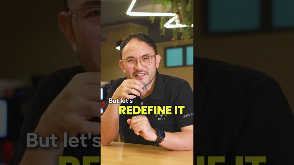 A presenter in an MHub polo shirt talking to camera in a cafe, with the on-screen caption "But let's redefine it".
