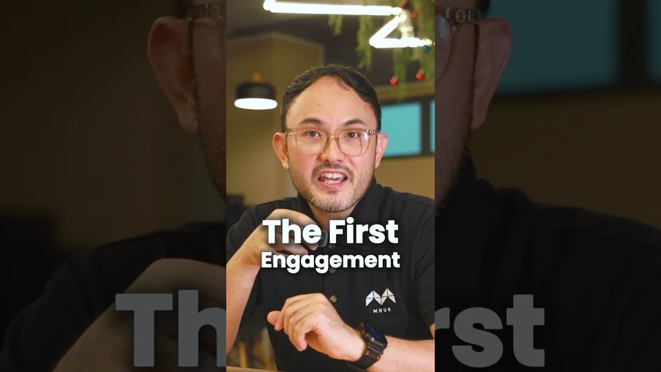 A presenter in an MHub polo shirt talking to camera in a cafe, with the on-screen caption "The first engagement".