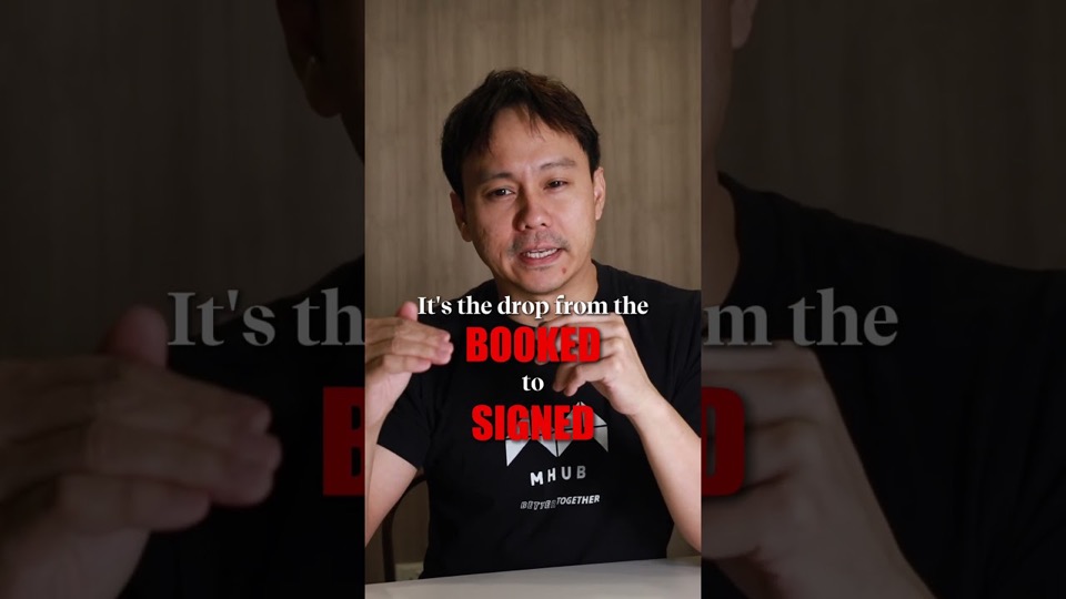 A presenter in a black MHub t-shirt talking to camera, with the on-screen caption "It's the drop from the booked to signed".